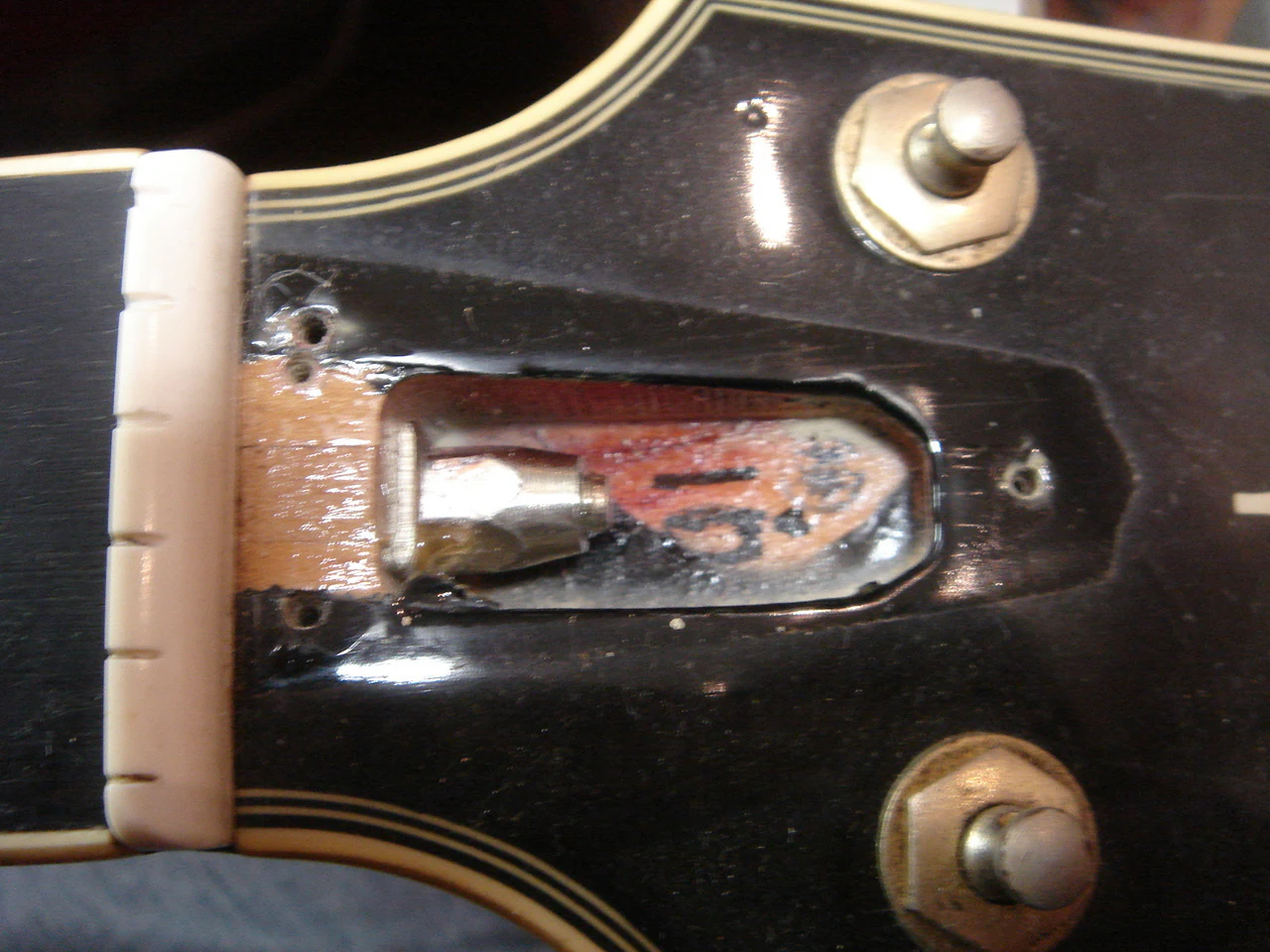 Off-center screw holes beneath the truss rod cover